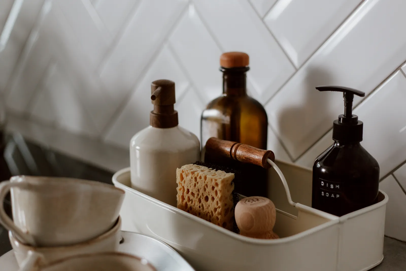 Considered, neutral-toned home cleaning essentials beside a kitchen sink